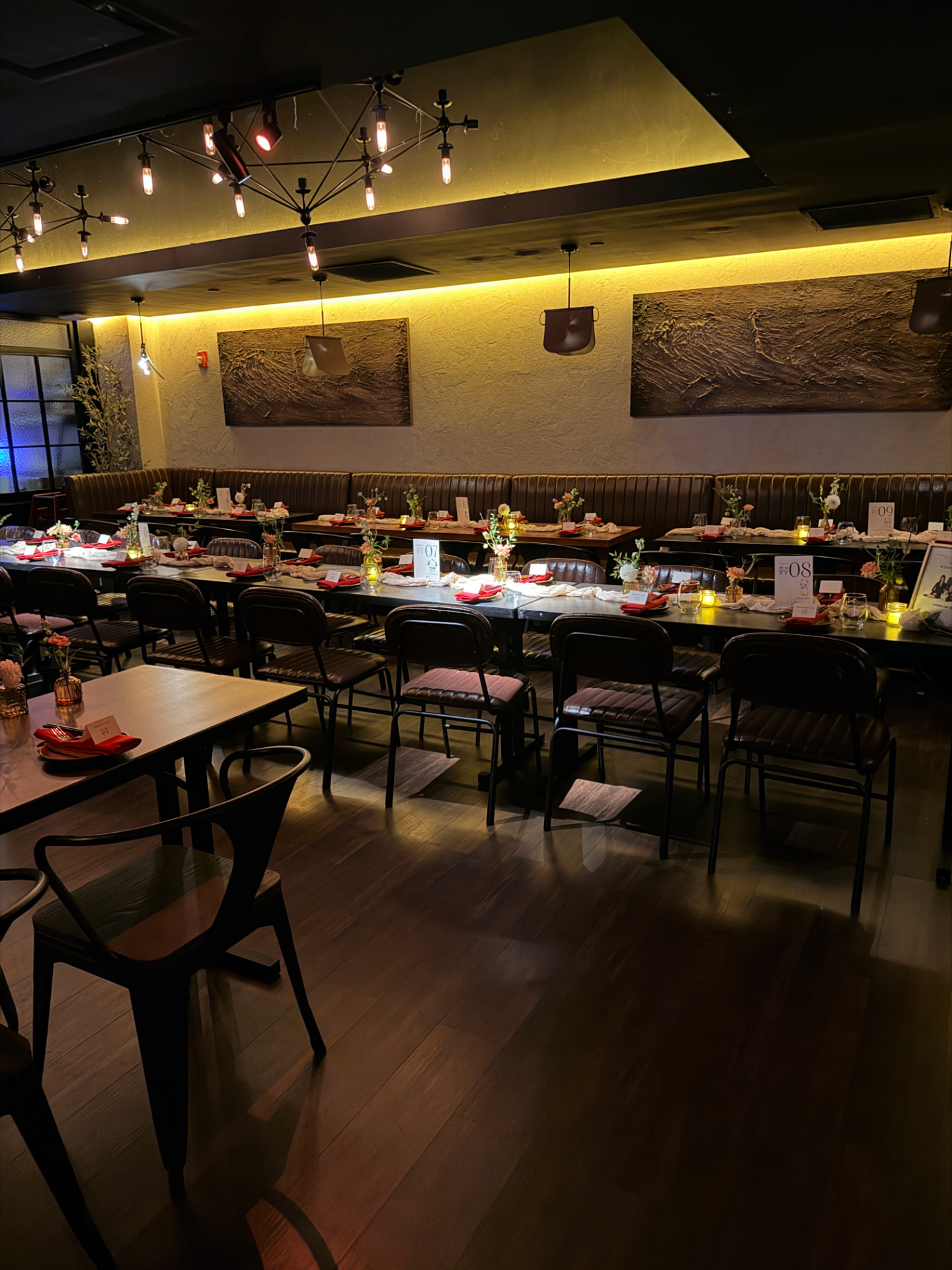 Main dining room set with long candlelit tables and flowers for a private dinner