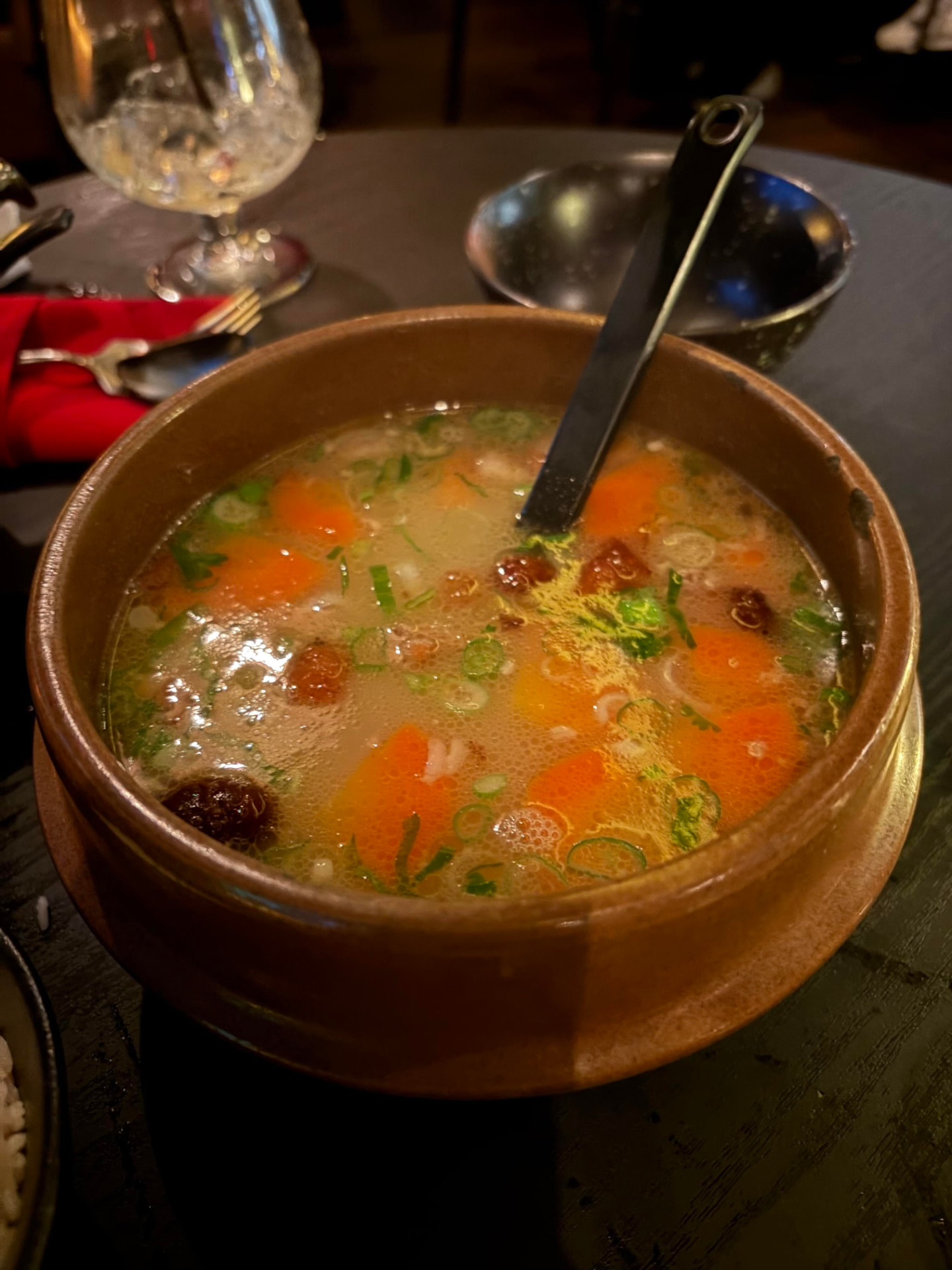 Clay bowl of duck bone soup with carrots and scallions